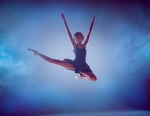 istock The silhouette of young ballet dancer jumping on a blue 498747898