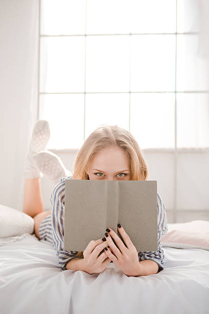 istock Playful girl hiding her face behind the book 498758278