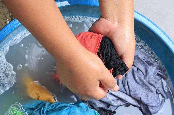 istock washing clothes by hand in plastic tubs 498759018