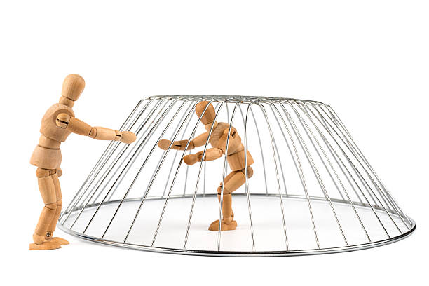 istock Wooden Mannequin isolated and trapped in a cage 498764411