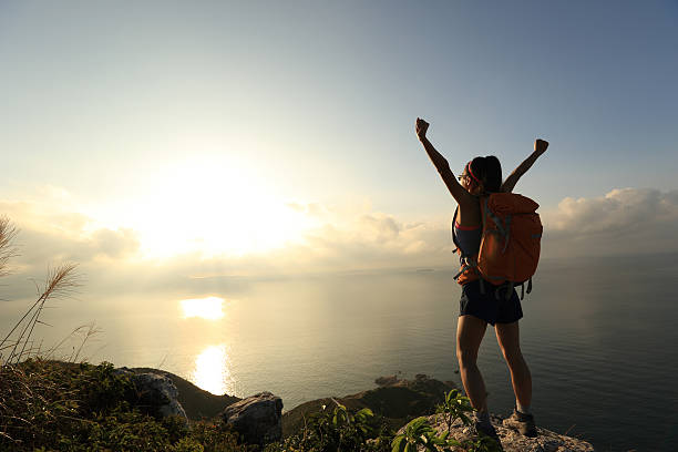 istock cheering young woman backpacker at sunrise seaside mountain peak 498765026