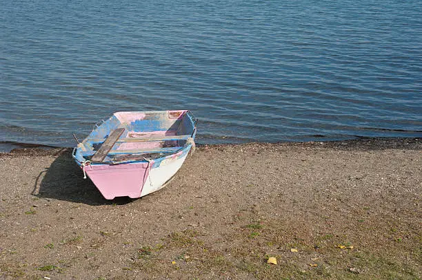 View of an abandoned old pink and blue boat beside Lago de Bracciano, Lazio, Italy.