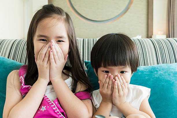istock girl and boy shutting up thier mouthes 498765225