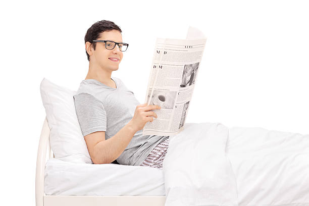 homem deitado na cama e ler um jornal - mattress newspaper reading bed imagens e fotografias de stock