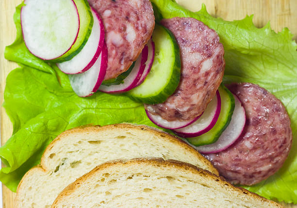 white bread with radish, cucumber and sausage on salad