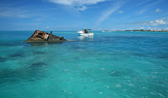 A ship wreck in a tropical sea, with a pleasure boat floating close by