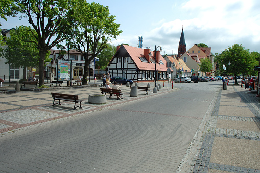 Ustka, Poland - May 24, 2014: Buildings, benches, unidentified people and cars on cobblestone street in Ustka, Poland.