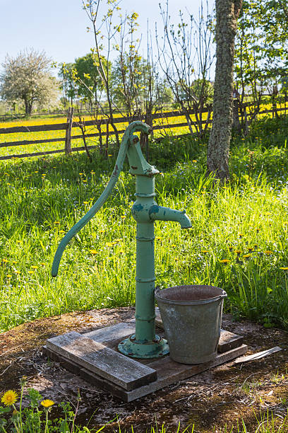 Hand operated water pump Hand operated water pump with bucket in the garden old fashioned well hand pump stock pictures, royalty-free photos & images