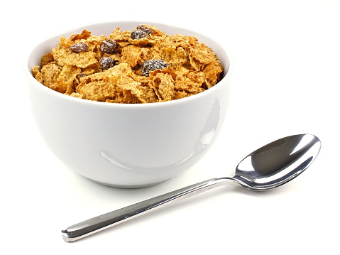 Bowl of bran flakes and raisin cereal on a white background with spoon