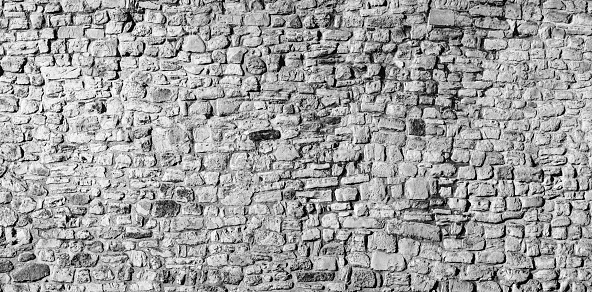 Panoramic old stone wall background in black and white