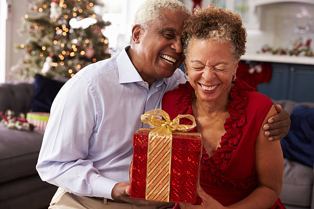 年配のカップルでのクリスマスプレゼントを交換する - giving christmas lifestyles holiday ストックフォトと画像