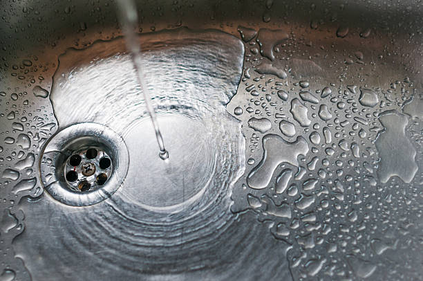 istock Stainless steel sink plug hole close up with water 498774212