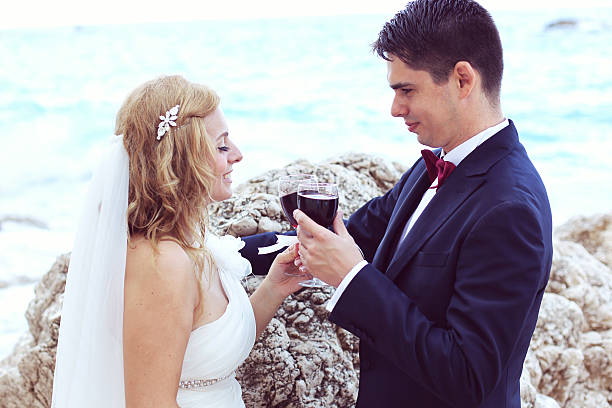 braut und bräutigam, trinkt rotwein auf das meer - wedding beach groom bride stock-fotos und bilder