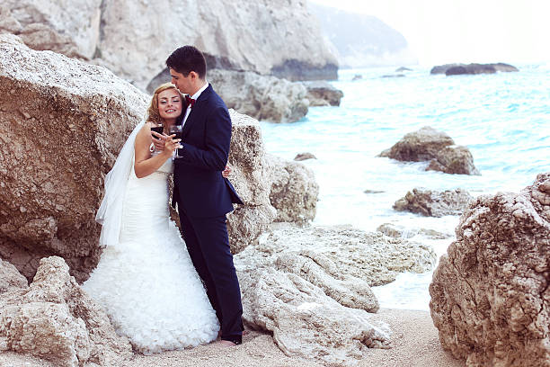 braut und bräutigam, trinkt rotwein auf das meer - wedding beach groom bride stock-fotos und bilder