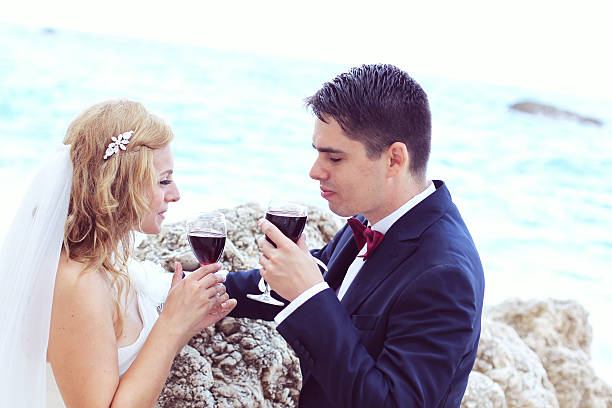 braut und bräutigam, trinkt rotwein auf das meer - wedding beach groom bride stock-fotos und bilder