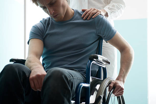 Doctor consoling young man sitting in wheelchair Female doctor consoling young man sitting in wheelchair invalid person stock pictures, royalty-free photos & images