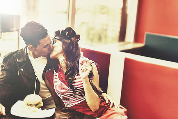 Kissing young couple in restaurant Kissing young couple in restaurant, textured image with aged effect, 50s years style. Slective Focus stock pictures, royalty-free photos & images