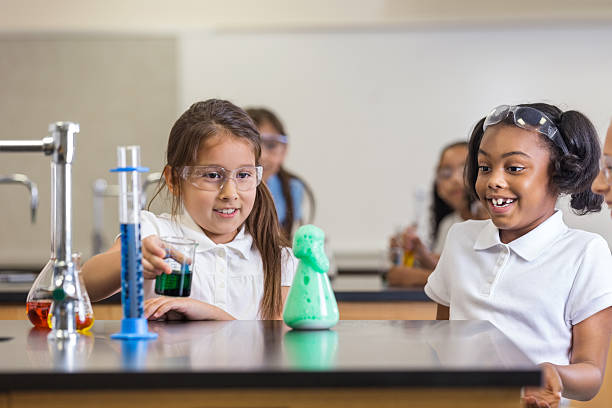 istock Excited little girls learning chemistry in science class 498787317