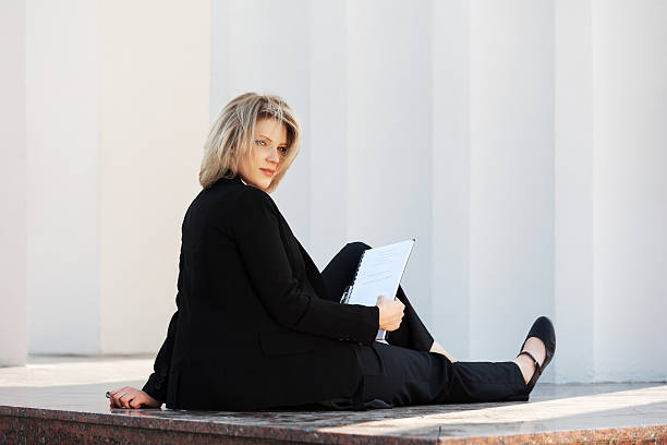 istock Young business woman with a folder sitting at the wall 498788165