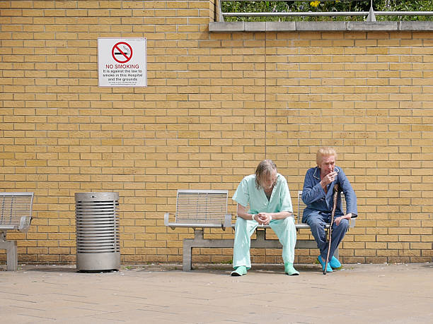 Hospital Patients Smoking London, UK - June 9, 2014: Candid capture of a pair of hospital patients taking a break from the ward to smoke a cigarette outside the Whittington Hospital, North London. anti tobacco day stock pictures, royalty-free photos & images