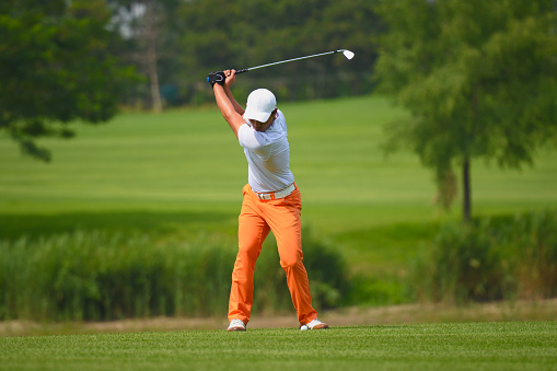 Male golfer plays golf on golf course. Golfer hitting golf ball