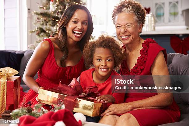 Girl With Grandmother And Mother Opening Christmas Gifts Stock Photo - Download Image Now