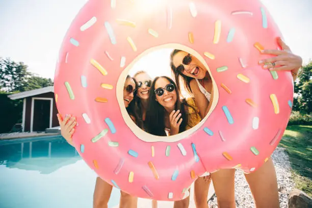 Photo of Girls laughing while holding a pool inflatable like a frame