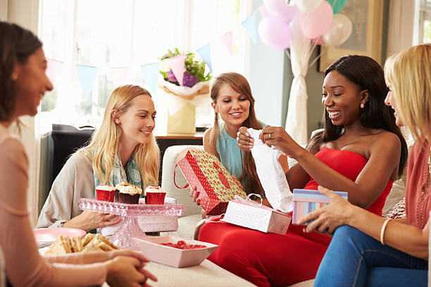 group of female friends meeting for baby shower at home - babyshower stockfoto's en -beelden