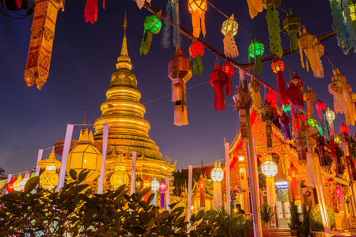 Gold pagoda and lantern hung up on the rail to the prosperity in loy kratong festival at wat phra that haripunchai lamphun Thailand at night time