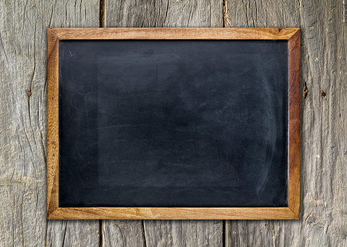 Front view of a blank blackboard over a weathered wooden surface