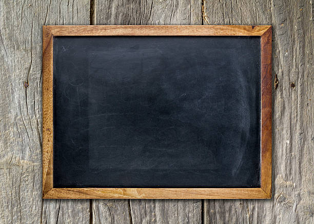 Empty chalkboard on wooden surface Front view of a blank blackboard over a weathered wooden surface chalk art equipment photos stock pictures, royalty-free photos & images