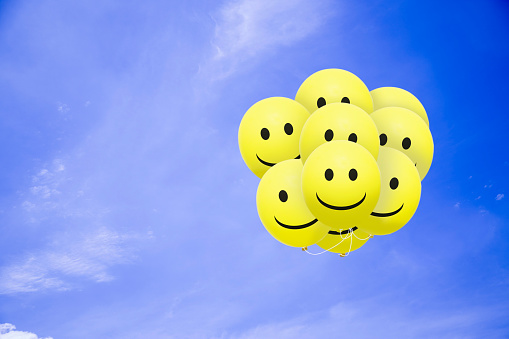 Bright balloons flying in the blue sky with a smiley