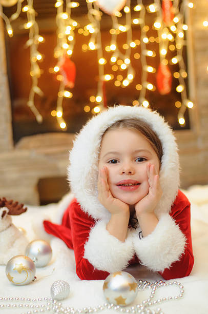 istock Little girl dressed as Santa by the fireplace 498808492