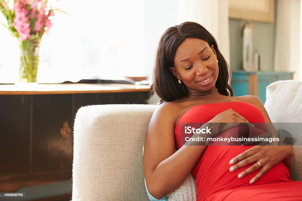 Pregnant Woman Relaxing On Sofa At Home African-American Ethnicity Stock Photo