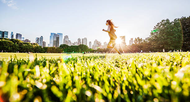 Girl runs in front of Manhattan skyline in Central Park Teenage girl runs in front of Manhattan skyline at the Sheep Meadow, Central Park, New York City. People relaxing ath the grass at evening.  teenage girls dusk city urban scene stock pictures, royalty-free photos & images