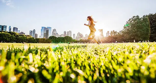 Photo of Girl runs in front of Manhattan skyline in Central Park