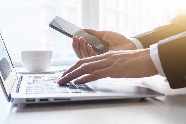istock Businessman using laptop and holding mobile phone 498809408