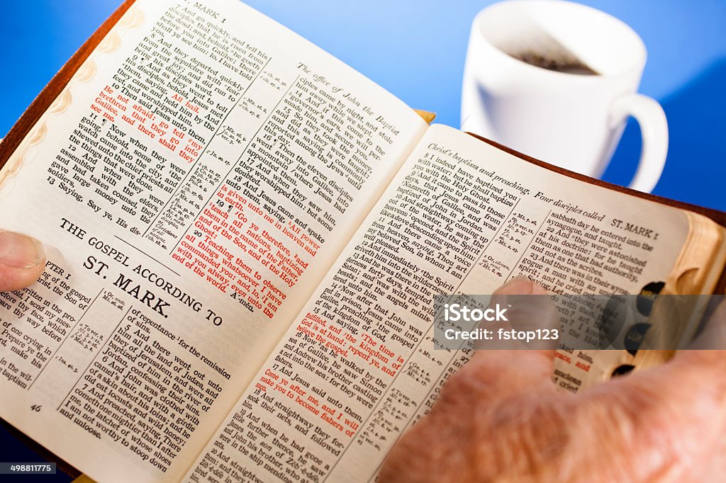 Senior homme tenant une Bible.  Il indique gospel de Mark.  Le Café - Photo de Adulte libre de droits