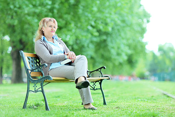 istock Mature lady relaxing in a park seated on bench 498815663