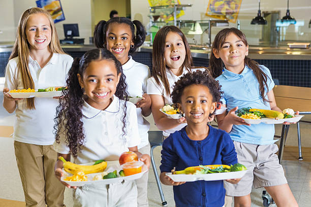 scuola elementare felice ragazze in uniformi con pranzo standard - child food school children eating foto e immagini stock