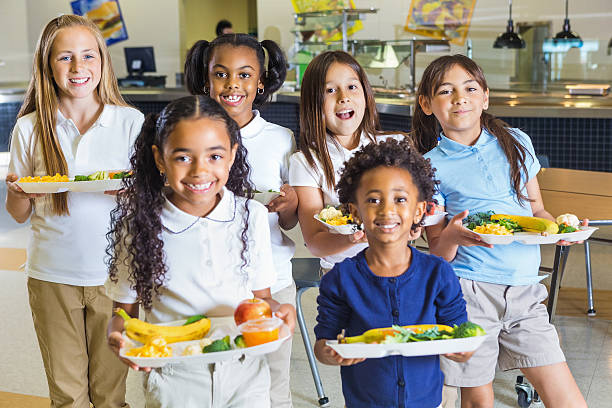 happy elementary school girls in uniforms holding lunch trays - schoollunch stockfoto's en -beelden