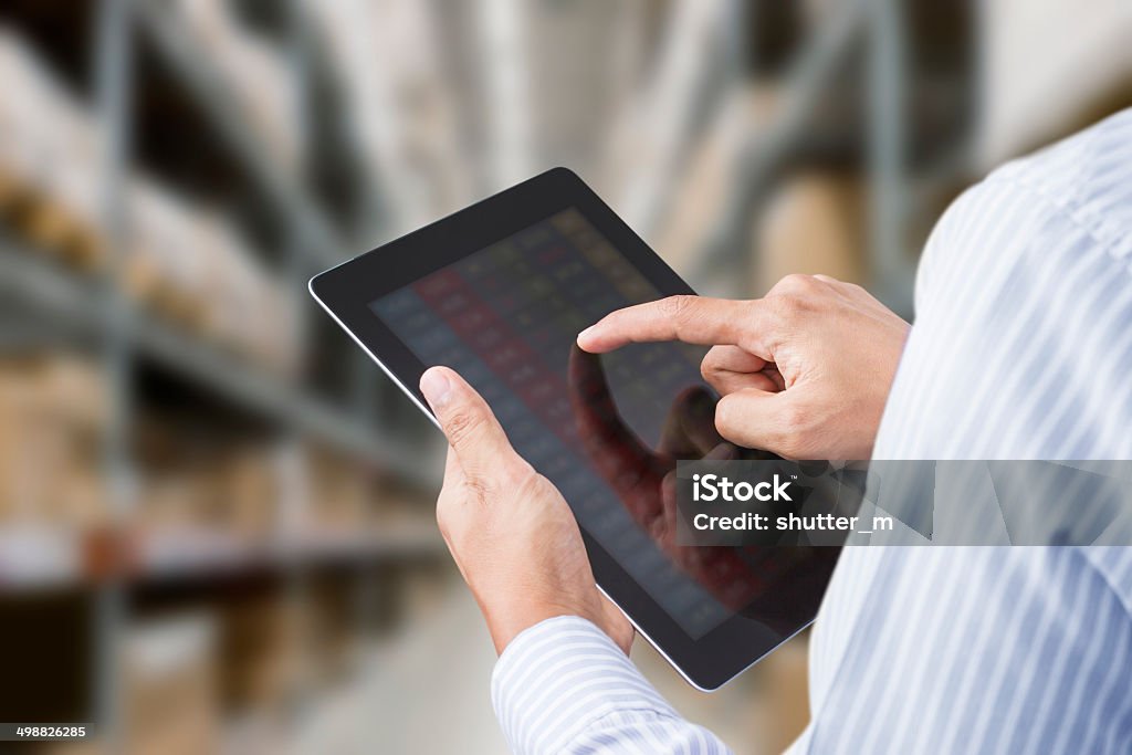 Businessman checking inventory in stock room on touchscreen tablet Businessman checking inventory in stock room of a manufacturing company on touchscreen tablet Warehouse Stock Photo