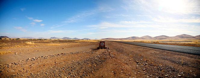 Panorama of tarred road to Sossusvlei area with sign road, mountains and desert all around, Namib Desert