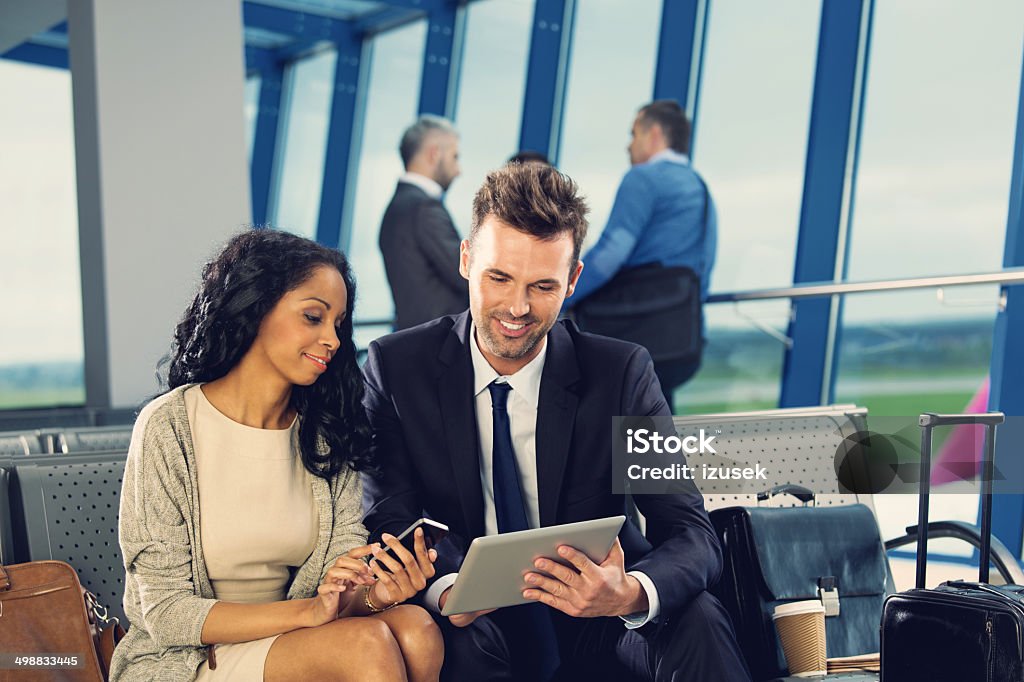 Waiting for the flight Two business people waiting for the flight in the airport lounge and using a digital tablet and smart phone. Airport Stock Photo