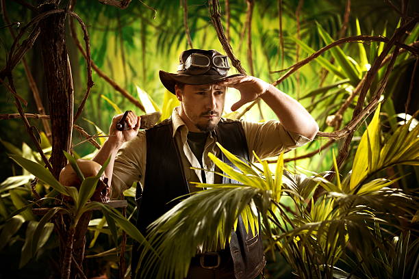 Walking in the jungle Young confident adventurer in the jungle holding a machete and looking around. Machete stock pictures, royalty-free photos & images