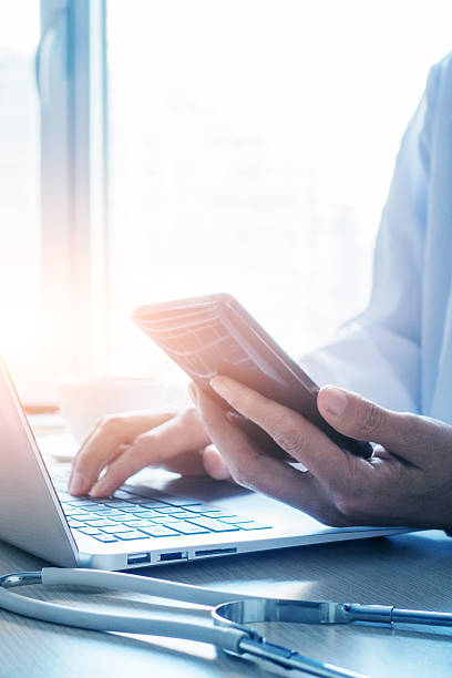 istock Doctor using smartphone and laptop in office 498834064