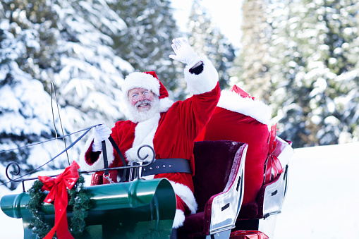 Santa Claus at the North Pole sitting in his sleigh waving to the camera. Copy space.
