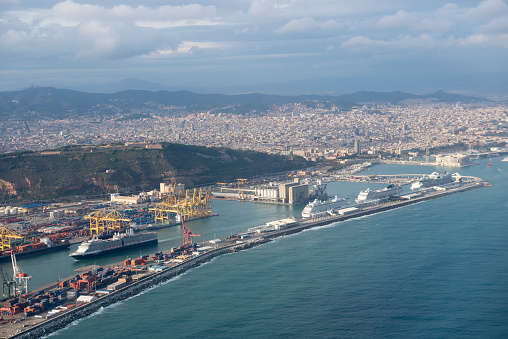 Barcelona, Spain - November 3, 2015: An aerial view of four cruise ships, three of them docked and one underway, in the port of Barcelona, Spain. The cruise lines include Crystal Cruises, Holland America, and MSC Cruises.