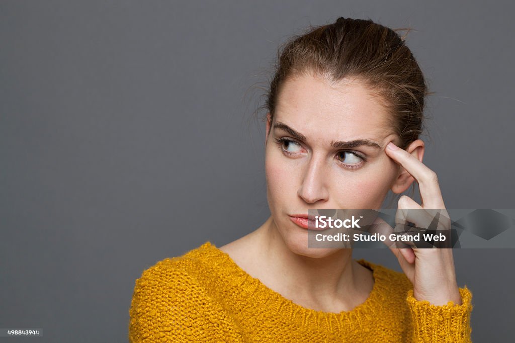 unhappy young woman looking dubious,expressing confusion and mistrust doubt and confusion concept - portrait of annoyed beautiful 20s girl in reflection,seeking for solutions,studio shot on gray background Disbelief Stock Photo