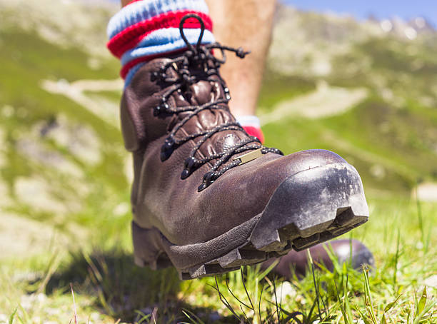 Close-up on a man's leather hiking boots as he steps forward while walking in the European Alps.